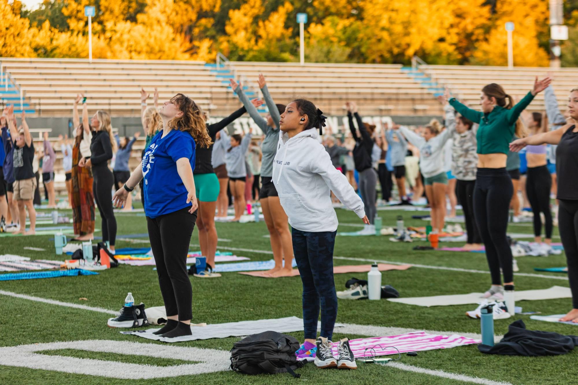 students take a yoga class on the football field.